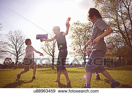 Boys playing with foam dart guns in park View Large Photo Image Stock Photo - Boys playing with foam dart guns in park. Fotosearch
