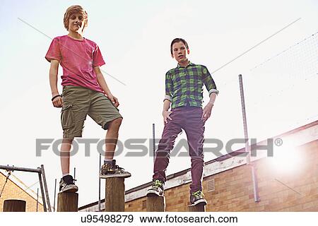 Stock Photo - Boys standing on wooden poles. Fotosearch