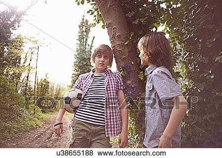 Boys talking by tree with football View Large Photo Image Stock Photo - Boys talking by tree with football. Fotosearch