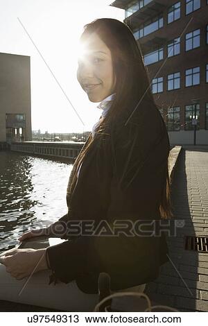 Stock Image - Business woman taking break by waterfront, Copenhagen, Denmark. Fotosearch