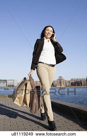 Stock Photo - Business woman walking using smartphone, Copenhagen, Denmark. Fotosearch