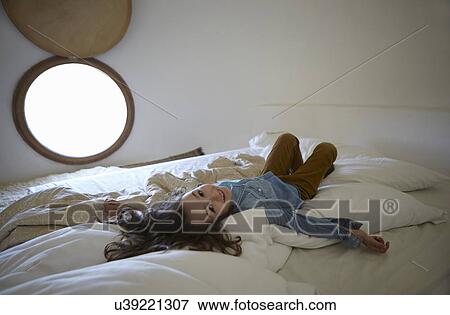 Stock Photo - Candid portrait of girl lying on bed. Fotosearch