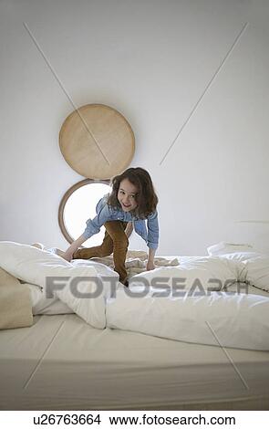 Picture - Candid portrait of girl playing on bed. Fotosearch