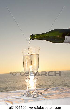 Champagne being poured into flute against sunset View Large Photo Image Stock Photo - Champagne being poured into flute against sunset. Fotosearch