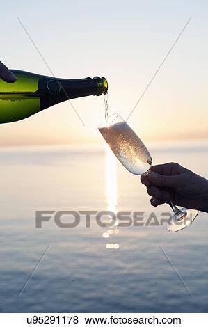 Champagne being poured into flute against sunset View Large Photo Image Stock Photo - Champagne being poured into flute against sunset. Fotosearch