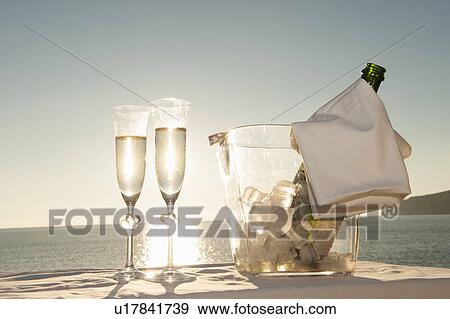 Stock Photo - Champagne flutes and bucket against sunset. Fotosearch