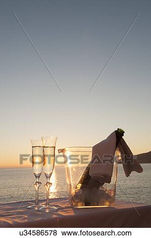Champagne flutes and bucket against sunset View Large Photo Image Stock Photo - Champagne flutes and bucket against sunset. Fotosearch