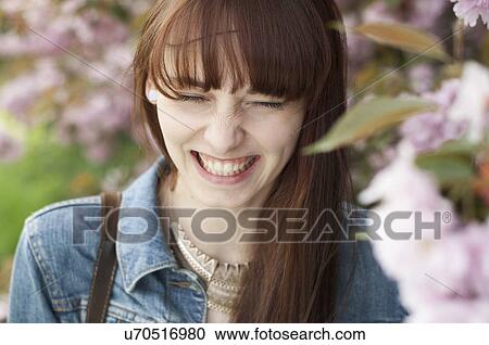 Stock Image - Close up portrait of young woman smiling with eyes closed. Fotosearch