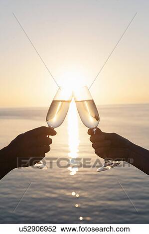 Stock Image - Couple toasting against sunset. Fotosearch