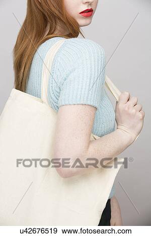 Stock Photo - Cropped image of young woman carrying shopping bag. Fotosearch