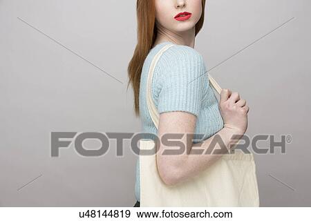Stock Photo - Cropped image of young woman carrying shopping bag. Fotosearch