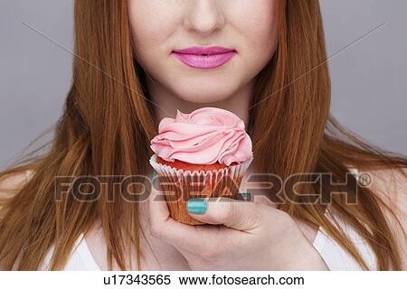 Cropped image of young woman holding cupcake View Large Photo Image Stock Photography - Cropped image of young woman holding cupcake. Fotosearch