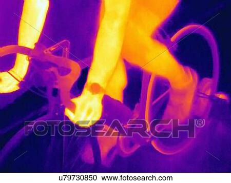 Stock Image - Cropped thermal image of young male athlete in training, showing the heat of the muscles and of the bicycle tires. Fotosearch