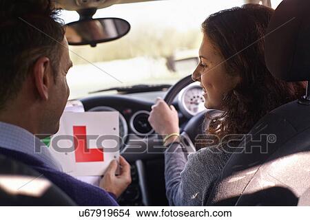 Picture - Driving instructor showing Learner Plate to learner driver. Fotosearch
