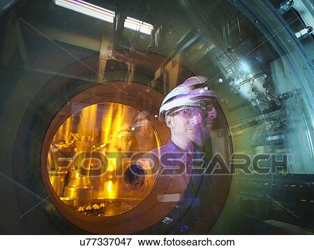 Stock Photo - Engineer reflected in glass of fuel rod handling machine in nuclear power station. Fotosearch