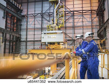 Stock Image - Engineers inspecting reactor hall in nuclear power station. Fotosearch