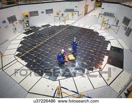 Stock Photograph - Engineers using sensors on pile cap in nuclear power station, high angle view. Fotosearch
