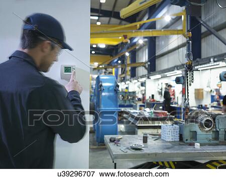 Factory worker adjusting thermostat in factory View Large Photo Image Stock Photo - Factory worker adjusting thermostat in factory. Fotosearch