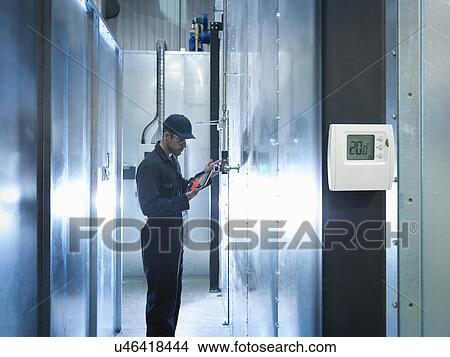 Factory worker using digital tablet to check power use in factory View Large Photo Image Picture - Factory worker using digital tablet to check power use in factory. Fotosearch