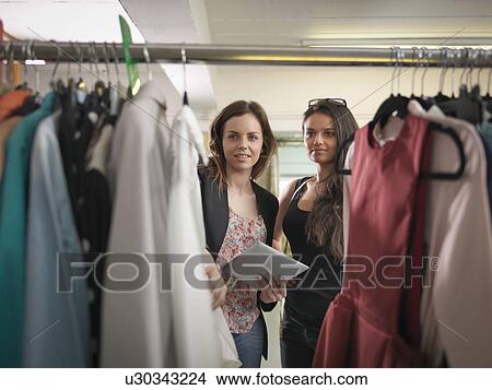 Picture - Fashion designers using digital tablet and inspecting clothing in fashion design studio. Fotosearch
