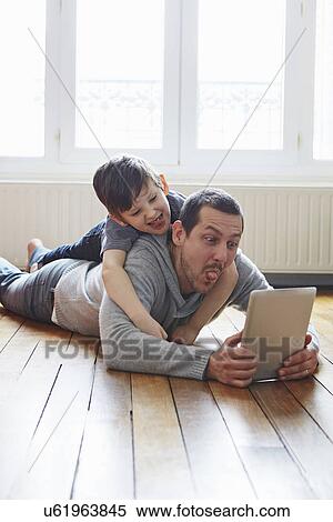 Stock Photography - Father and son self-photographing with digital tablet. Fotosearch