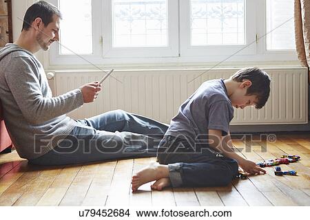 Father and son spending time in living room View Large Photo Image Picture - Father and son spending time in living room. Fotosearch