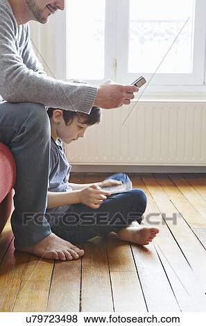 Stock Photo - Father and son spending time in living room. Fotosearch