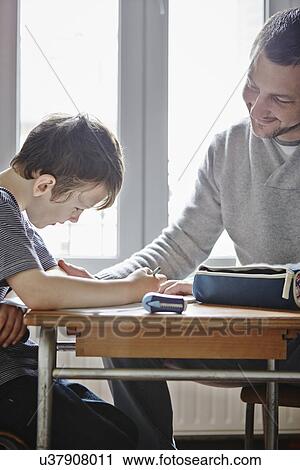 Stock Image - Father helping son with homework. Fotosearch