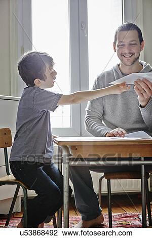 Stock Image - Father holding paper plane for son. Fotosearch