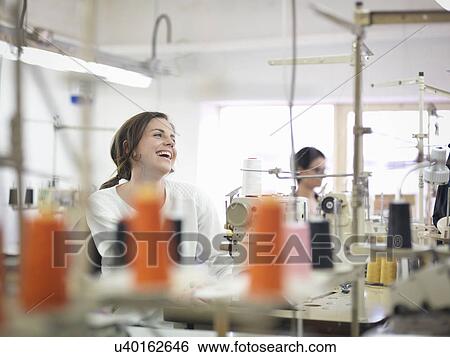 Stock Photograph - Female garment worker laughing in clothing factory. Fotosearch