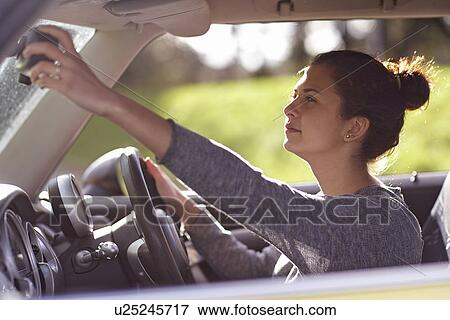 Stock Photo - Female learner driver adjusting rear view mirror. Fotosearch