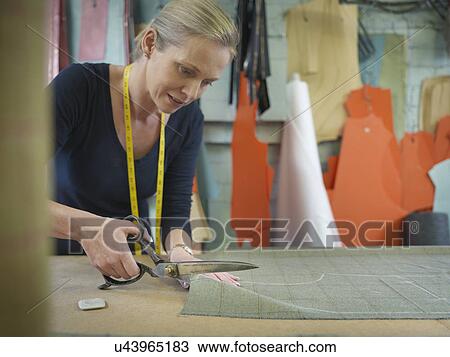 Stock Image - Female worker cutting cloth in garment factory. Fotosearch