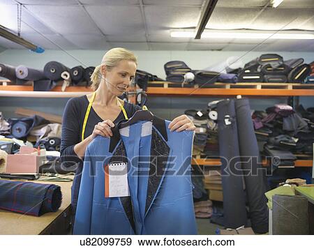 Stock Photo - Female worker inspecting jacket in clothing factory. Fotosearch