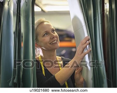 Stock Image - Female worker inspecting patterns in clothing factory. Fotosearch