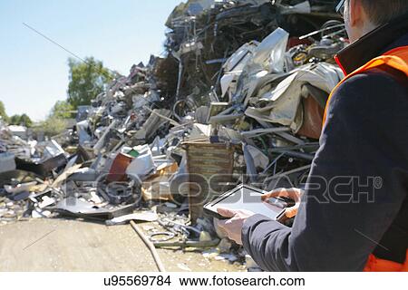 Foreman using digital tablet at scrap metal recycling plant View Large Photo Image Picture - Foreman using digital tablet at scrap metal recycling plant. Fotosearch