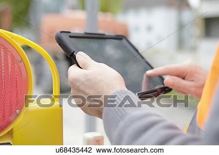Foremans hands using digital tablet on road construction site View Large Photo Image Stock Image - Foremans hands using digital tablet on road construction site. Fotosearch