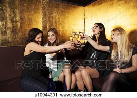 Four female friends toasting with wine in nightclub View Large Photo Image Stock Image - Four female friends toasting with wine in nightclub. Fotosearch