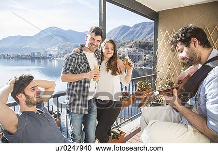 Four friends on balcony, with guitar and beer View Large Photo Image Stock Image - Four friends on balcony, with guitar and beer. Fotosearch