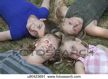 Stock Image - Four girls lying on grass. Fotosearch