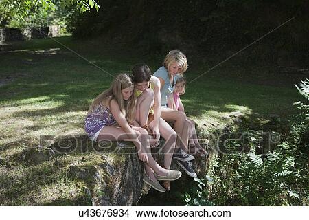 Picture - Four girls sitting in garden. Fotosearch