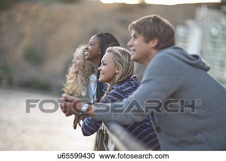 Four young adult friends gazing from riverside railings View Large Photo Image Stock Image - Four young adult friends gazing from riverside railings. Fotosearch