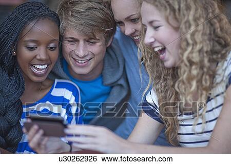 Four young adult friends looking at smartphone View Large Photo Image Stock Photograph - Four young adult friends looking at smartphone. Fotosearch
