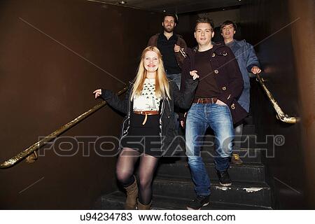 Stock Image - Friends coming down stairs into nightclub. Fotosearch