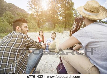 Stock Image - Friends sitting having picnic. Fotosearch
