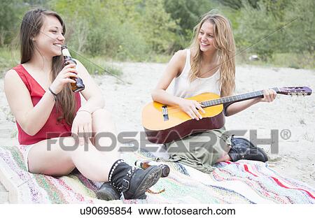 Friends sitting in field, playing guitar View Large Photo Image Picture - Friends sitting in field, playing guitar. Fotosearch