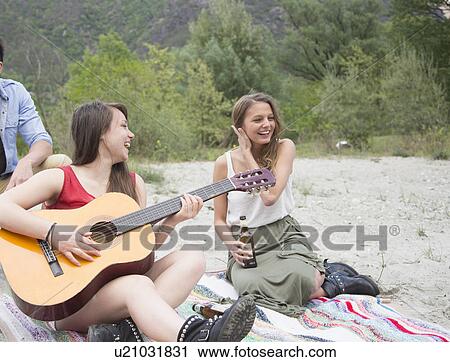 Friends sitting in field, playing guitar View Large Photo Image Stock Image - Friends sitting in field, playing guitar. Fotosearch