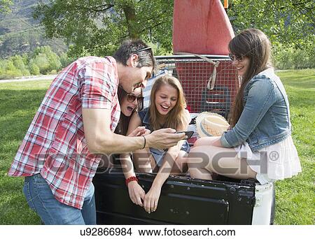 Picture - Friends sitting on back of off road vehicle. Fotosearch