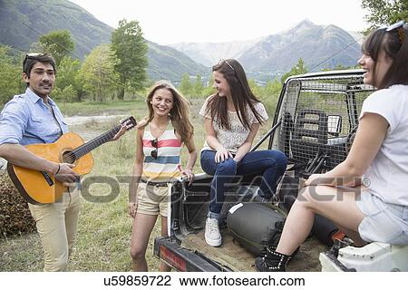 Stock Image - Friends sitting on back of off road vehicle. Fotosearch
