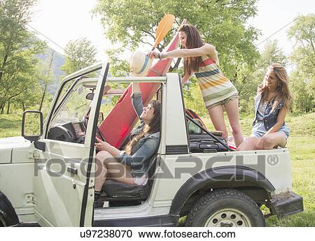 Stock Image - Friends sitting on back of off road vehicle. Fotosearch