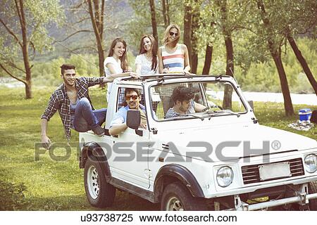 Stock Photography - Friends sitting on back of off road vehicle. Fotosearch